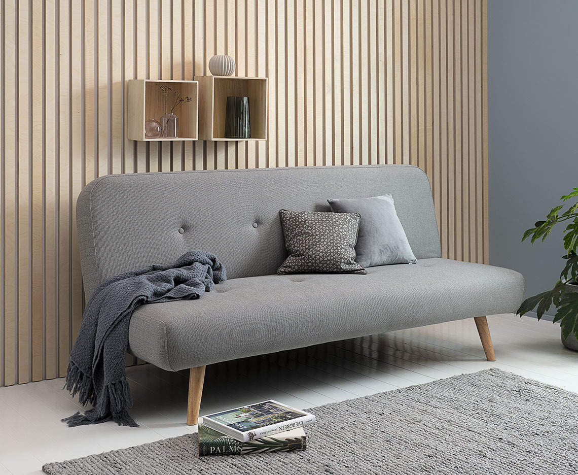 JUVRE sofa bed Light grey sofa bed with a throw, small cushions, and some books