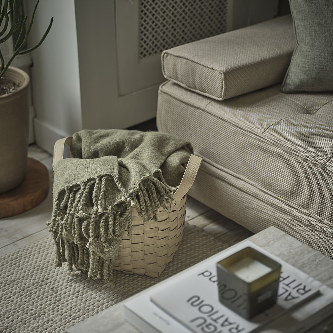 REINFANN throw Green throw in a basket standing next to a beige daybed