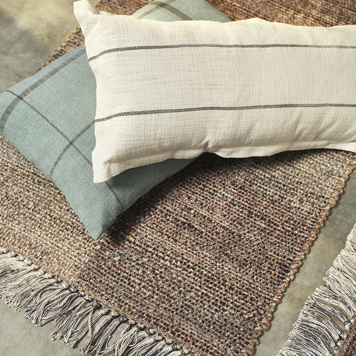 ENGSYRE rug and KLOKKELYNG and HALLON cushions Brown cushion and blue checkered cushion
