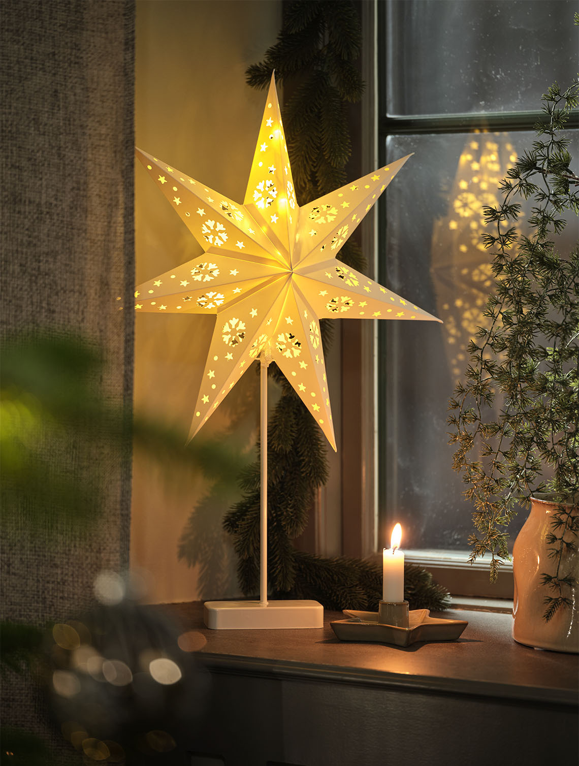 UNAKIT star-shaped light with built-in timer Star-shaped light illuminating a window inside a home