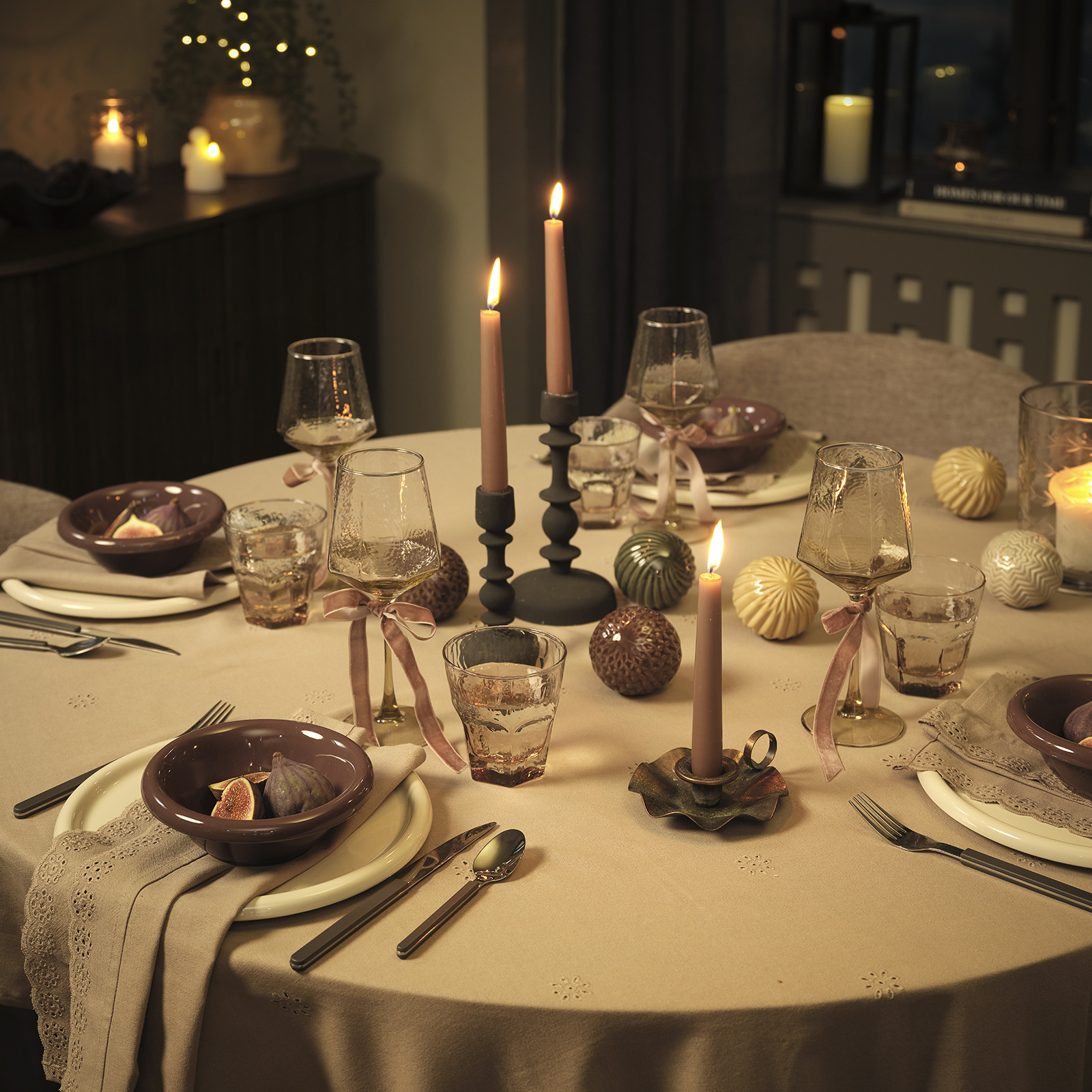 MALIK plates and bowls, GUNVALD drinking glasses and wine glasses, GYLFE candle holder and FERIE Christmas baubles Candlelit dinner table with plates, bowls, cutlery and ornaments