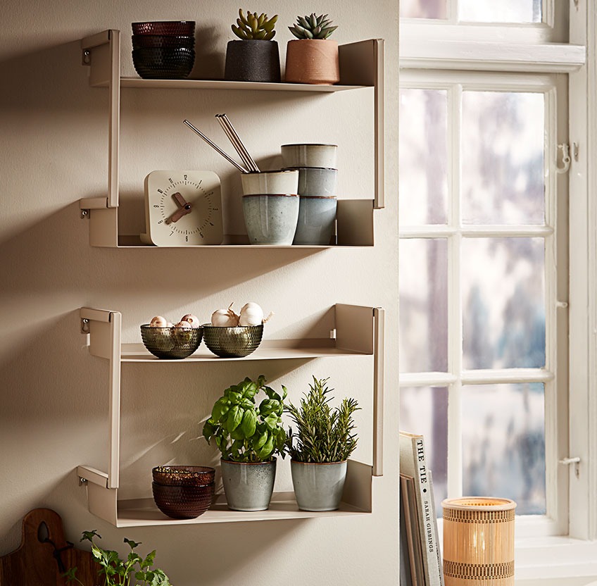 ASSENS wall shelf with LAUKE mugs, EDDIE clock and JONAS bowls Glass bowls, stoneware mugs and fresh herbs on a wall shelf in a kitchen