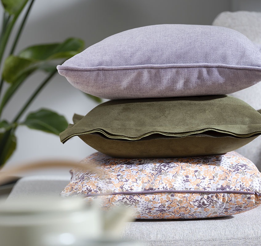 HORNFIOL purple cushion, green ALM and KAMILLE cushion with a floral print Stack with three cushions: one purple, one green and one with floral print