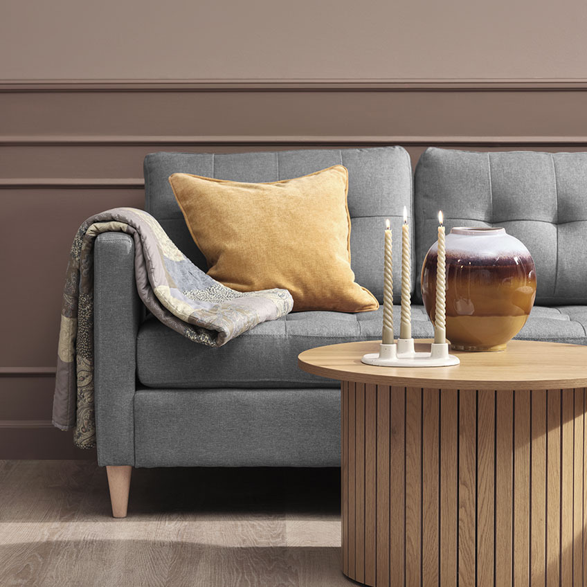 HUMLE quilted blanket and HORNFIOL cushion Quilted blanket and yellow cushion on grey sofa, wooden coffee table with candles and vase